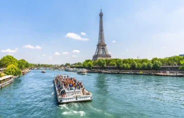 A view of the Eiffel Tower from a Parisian street with traditional cafes and cobblestone paths.